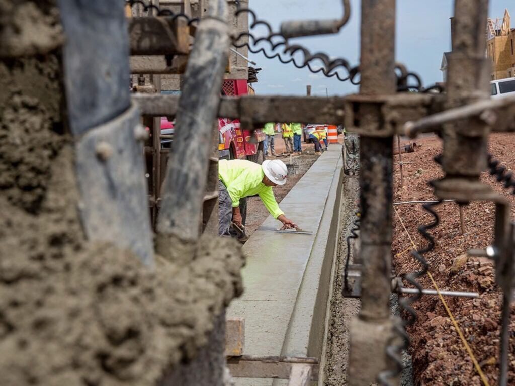 William A. Hazel employee performing site work on curb, amongst heavy equipment